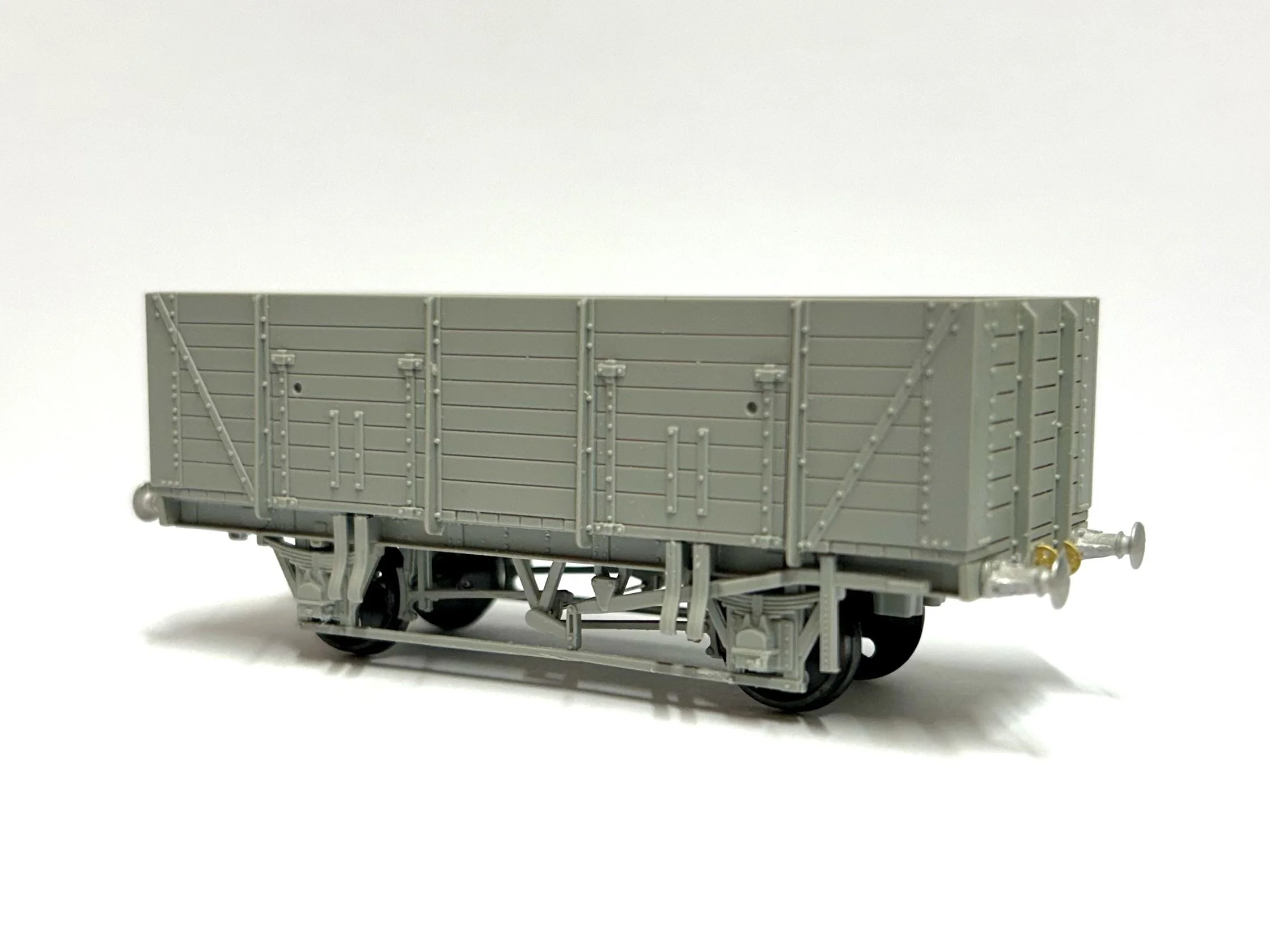 Miniature flatbed train car with wooden slats and metal frame, placed on a wooden surface.