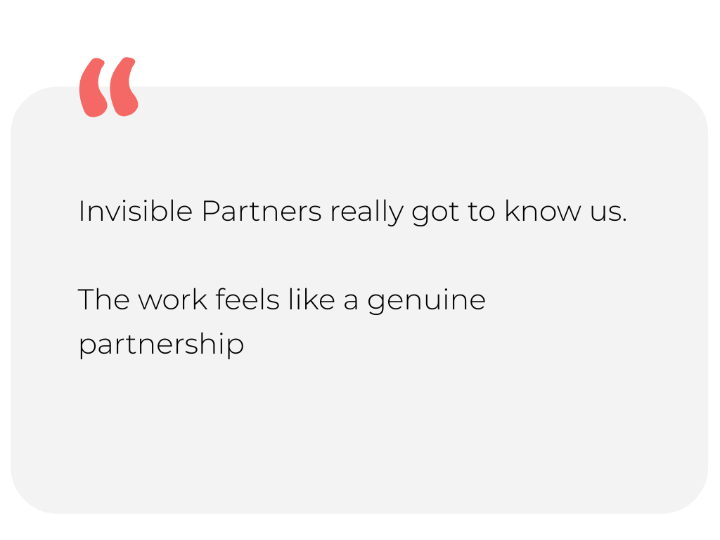 Scenic view of a mountain range across a body of water, with shoreline and trees in the foreground at sunset