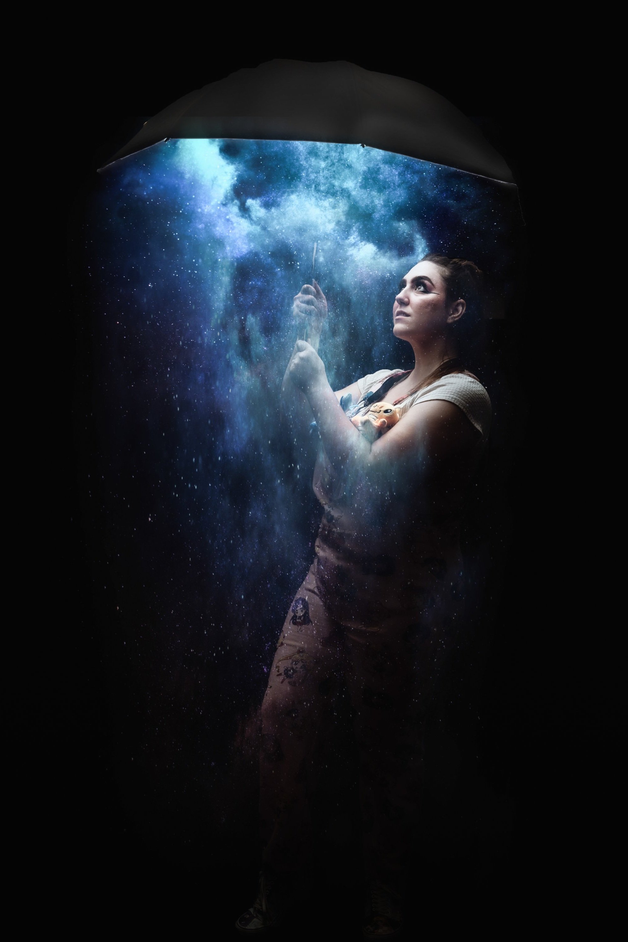 A woman holding a transparent umbrella that displays a starry night sky and galaxy, with a dark background.