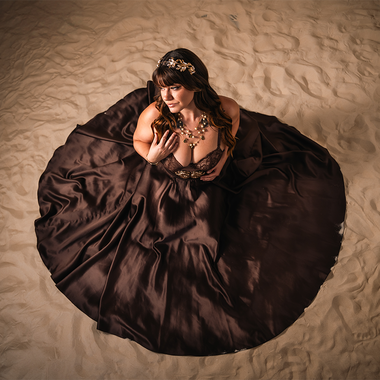 Portrait woman brown dress sand.png