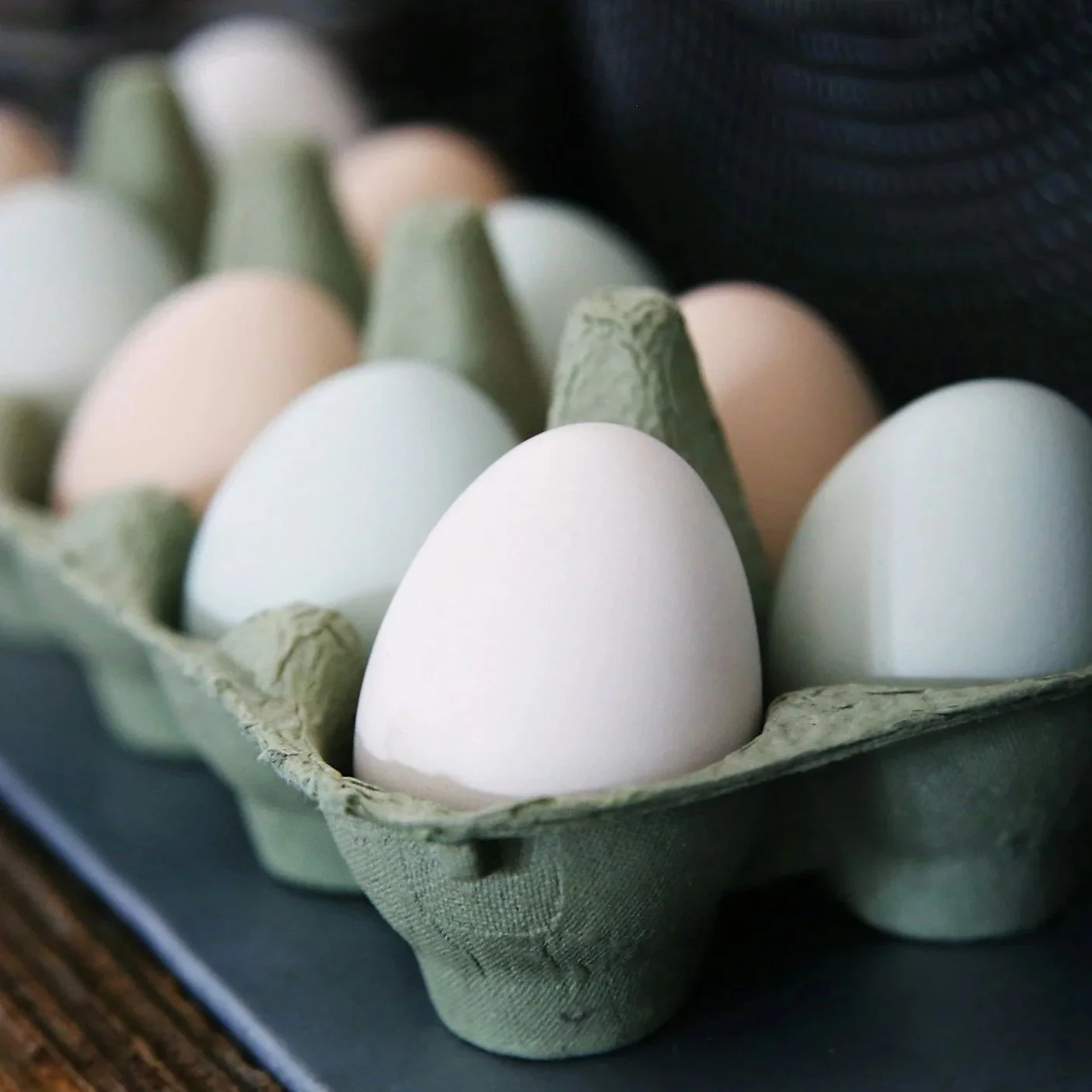Carton of multicolored eggs including white and pale green.