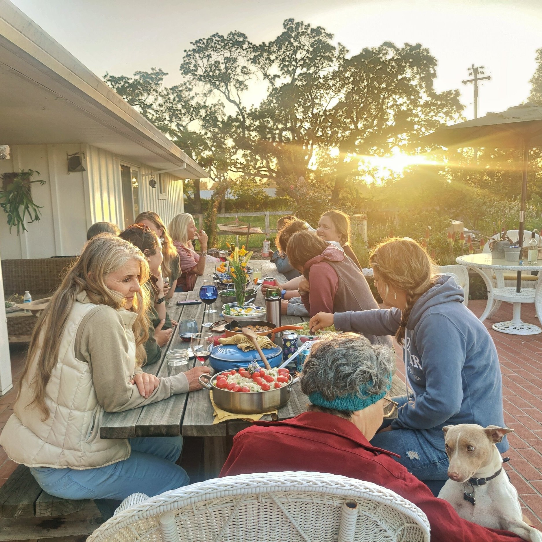 Group of dinner guests enjoying a meal on the back patio at Casari Ranch at sunset