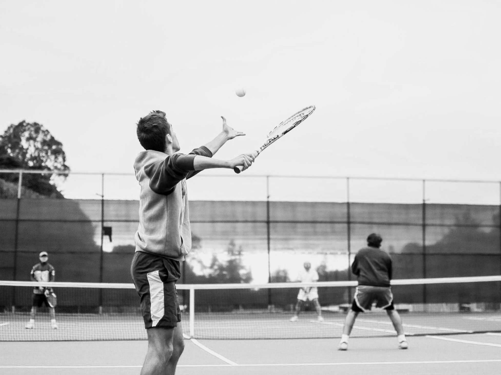 Group of people playing tennis on an outdoor court