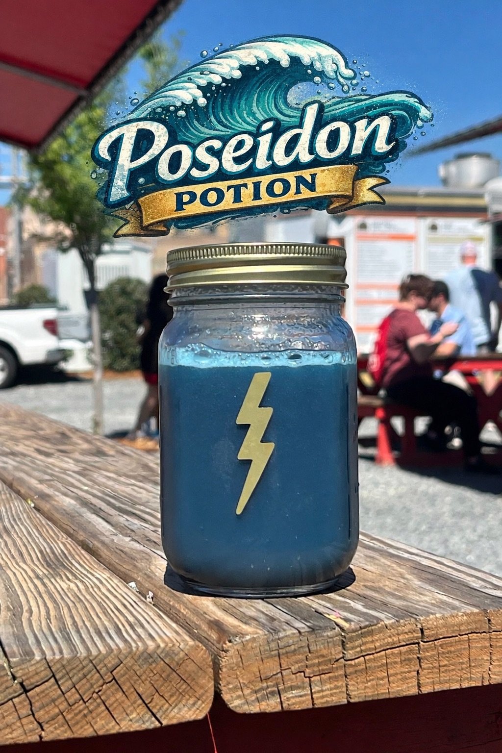A mason jar filled with a blue liquid, featuring a yellow lightning bolt on the front, sitting on a weathered wooden table outdoors with people in the background.