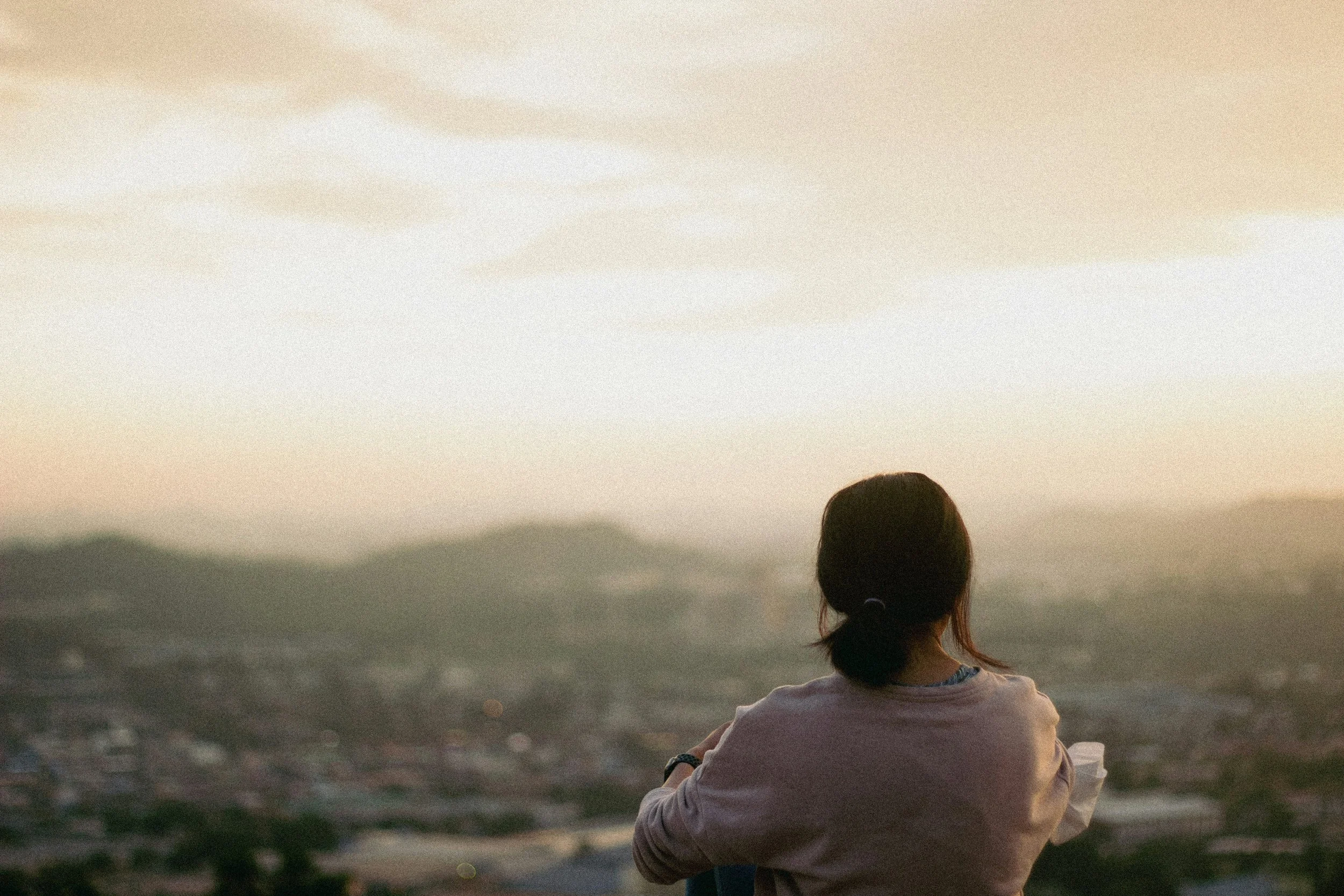 woman overlooking a city with mountains at dusk