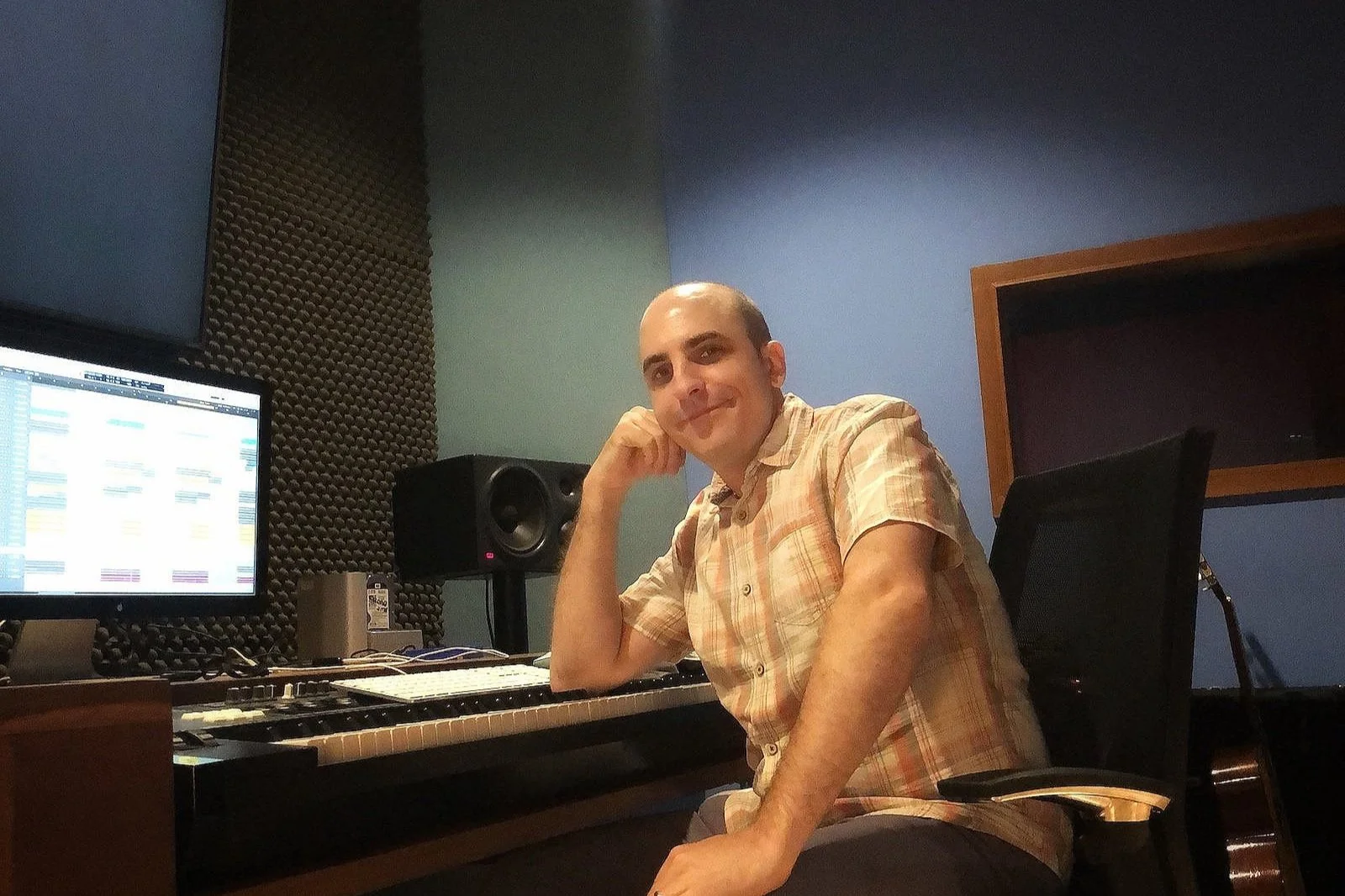 Nico sitting at a music production studio desk with sound mixing equipment and speakers