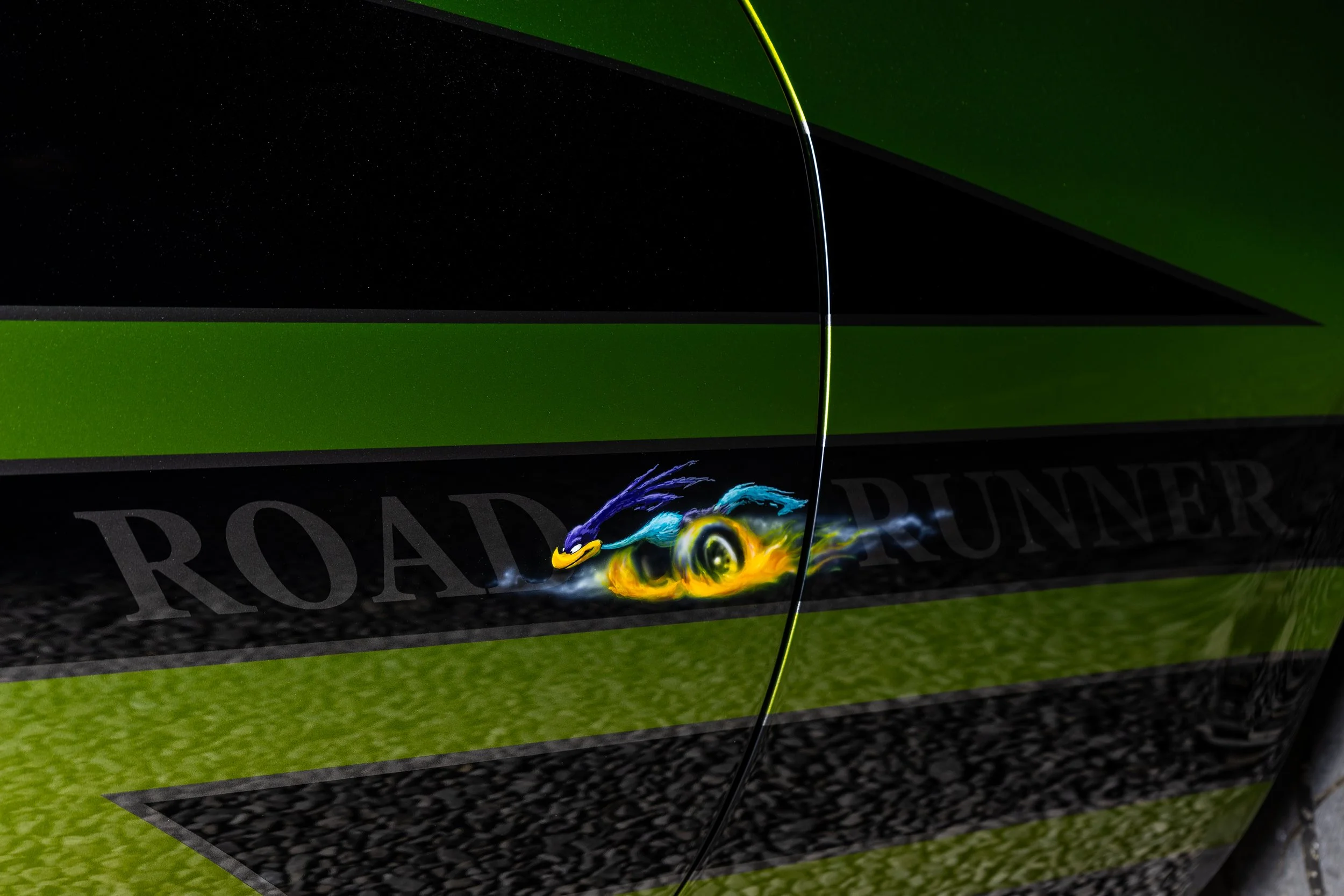 Close-up of a green and black vehicle door with a Dragon Ball Z character, Vegeta, painted as a decal, featuring the word 'ROADRUNNER' in black letters.