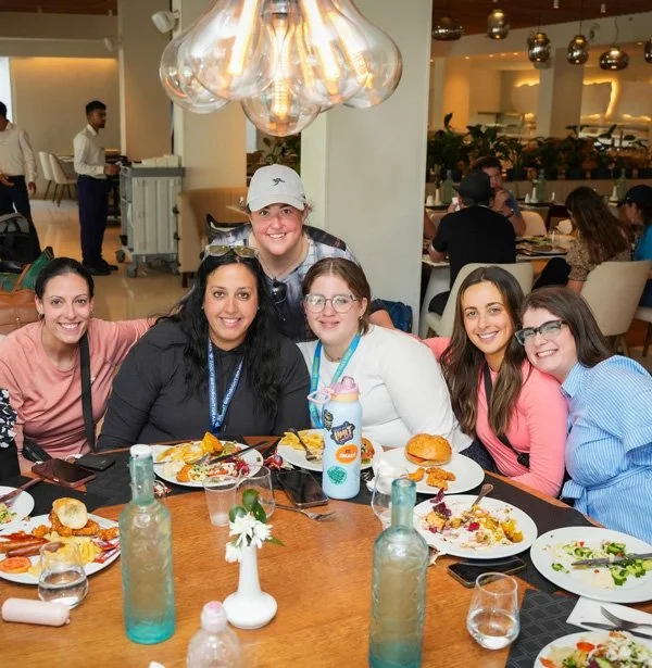 group of smiling young adults connecting and enjoying a meal together