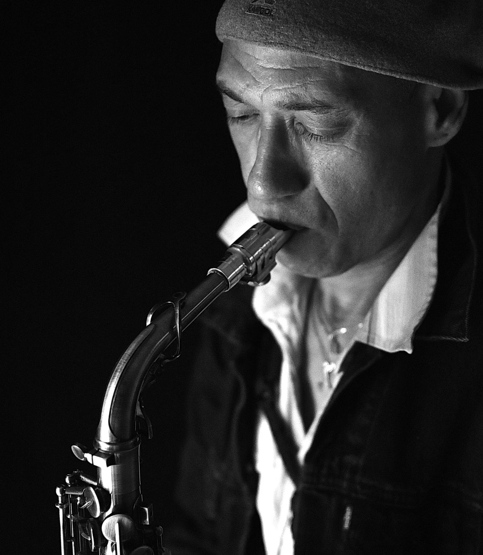 Jazzstemning med saxofonist i fokus

Mand spiller saxofon med lukkede øjne i sort-hvid nærbillede