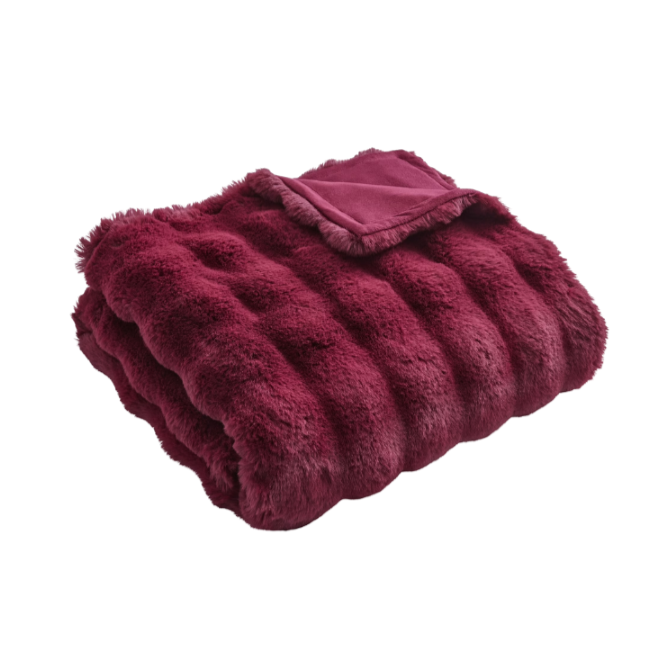 A folded maroon or deep red faux fur blanket with a matching pillow on top.