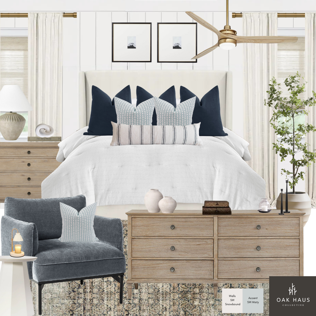 A bedroom with a white upholstered headboard, navy and patterned throw pillows on a white bed, and a wood dresser in front. The room has white curtains, a ceiling fan, and a potted plant. The decor includes framed art, vases, candles, and books.