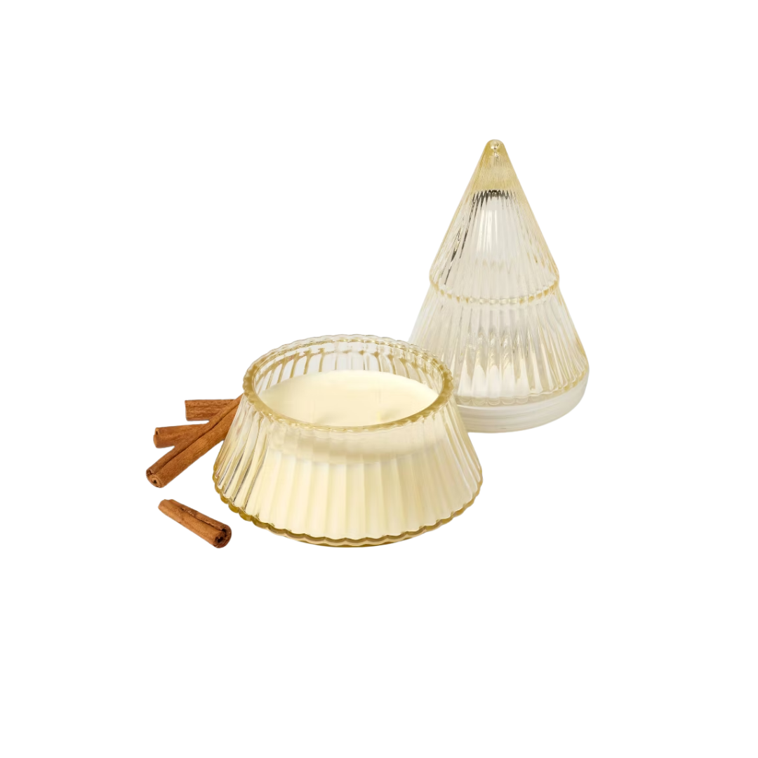 Decorative glass candle holder with a white candle, surrounded by cinnamon sticks.