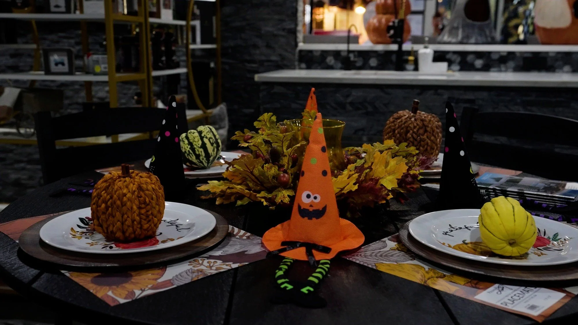 Seasonal showroom table display with fall decor, pumpkins, and outdoor fireplace setting