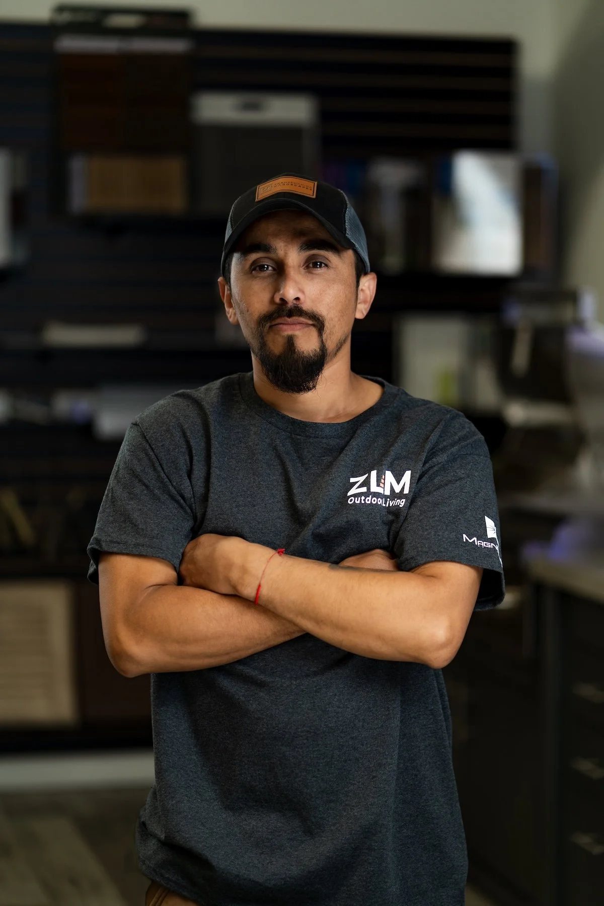 Man wearing a black hoodie with 'ZLM Services, LLC Outdoor Living' logo, standing indoors with wood samples in the background.