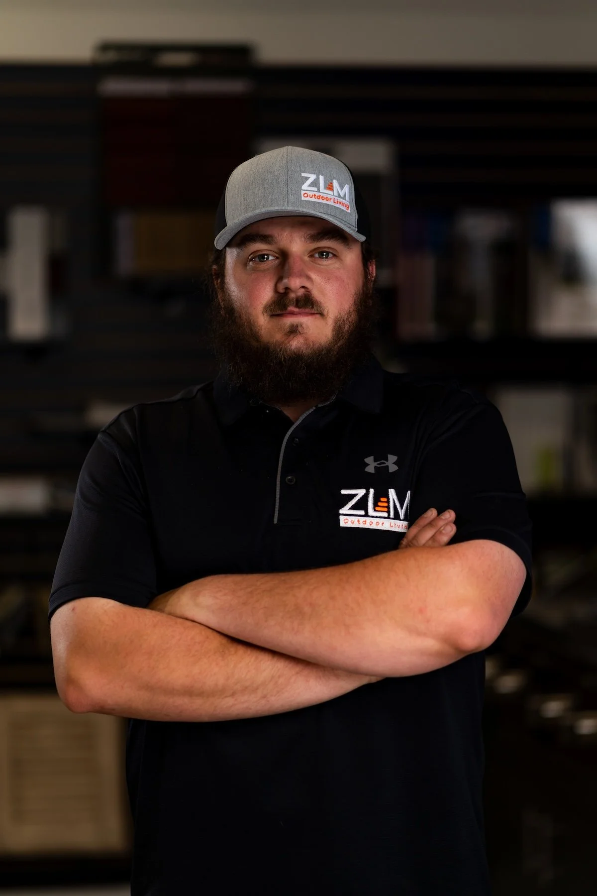 Man with long beard wearing black t-shirt and gray hate with ZLM logo