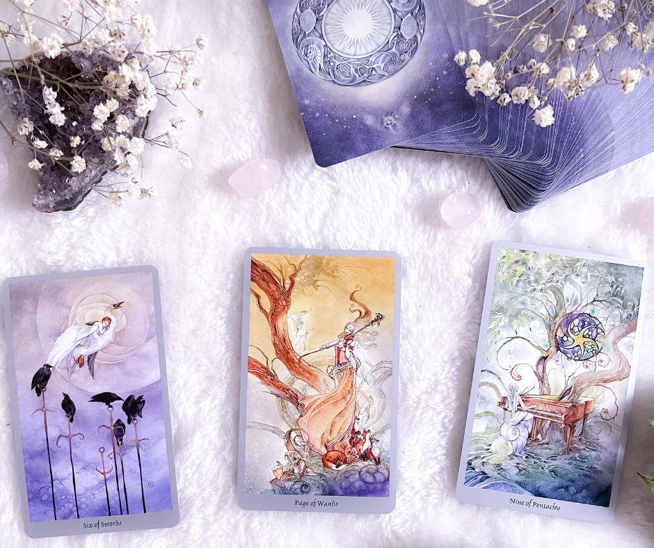 Three tarot cards are laid out on a white blanket