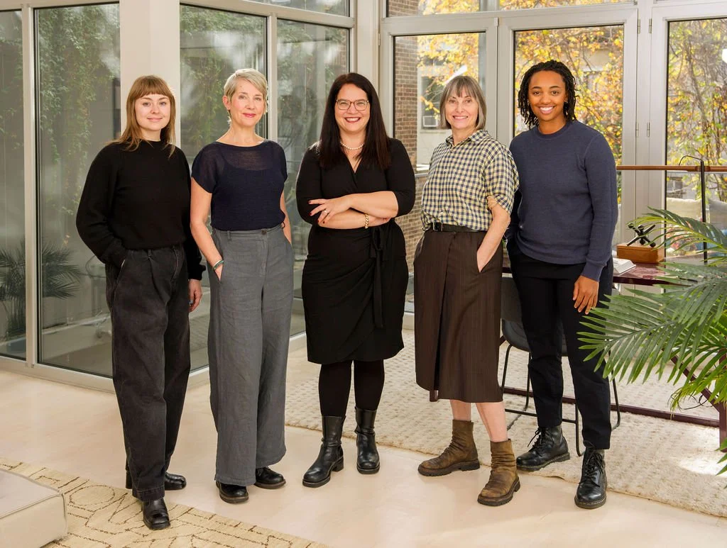 5 women dressed in neutrals posing in a townhouse