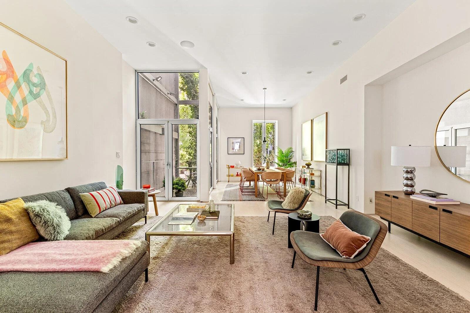large, recently refinished townhouse room with neutral furnishings and pops of earth-toned color