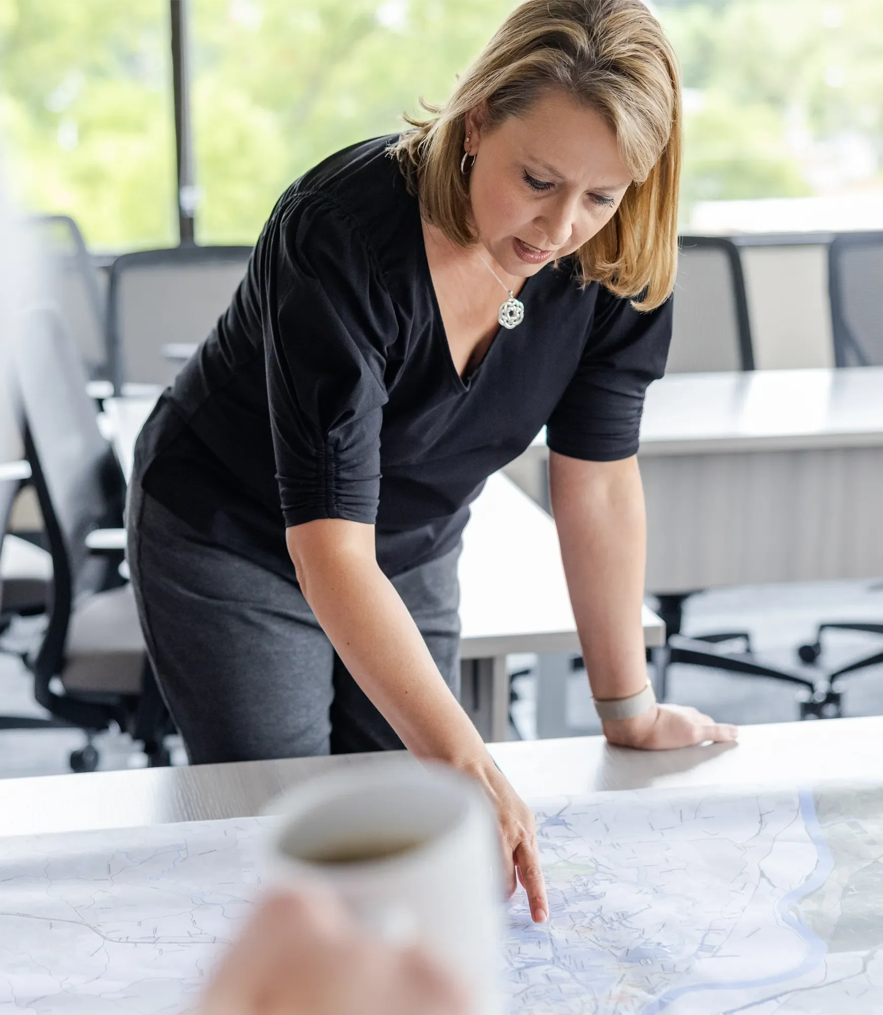Woman in an office leaning over a large map on a conference table