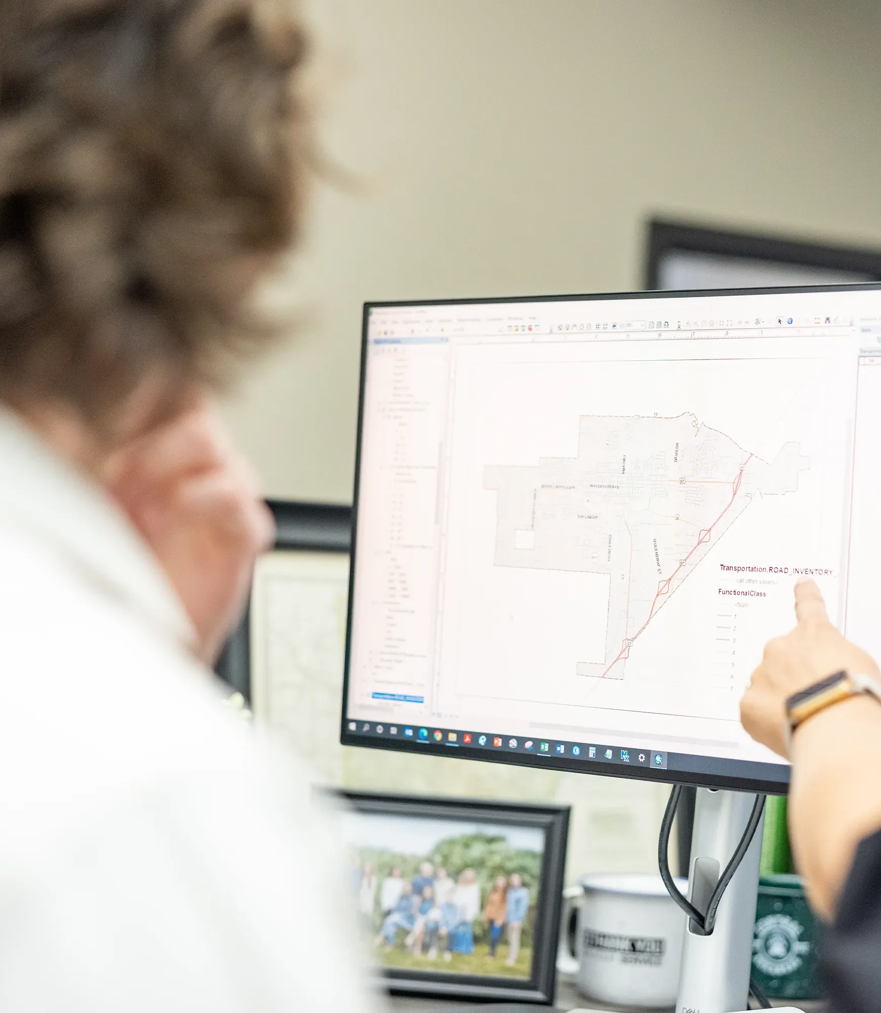 Person pointing at a computer monitor displaying a transportation road inventory map.