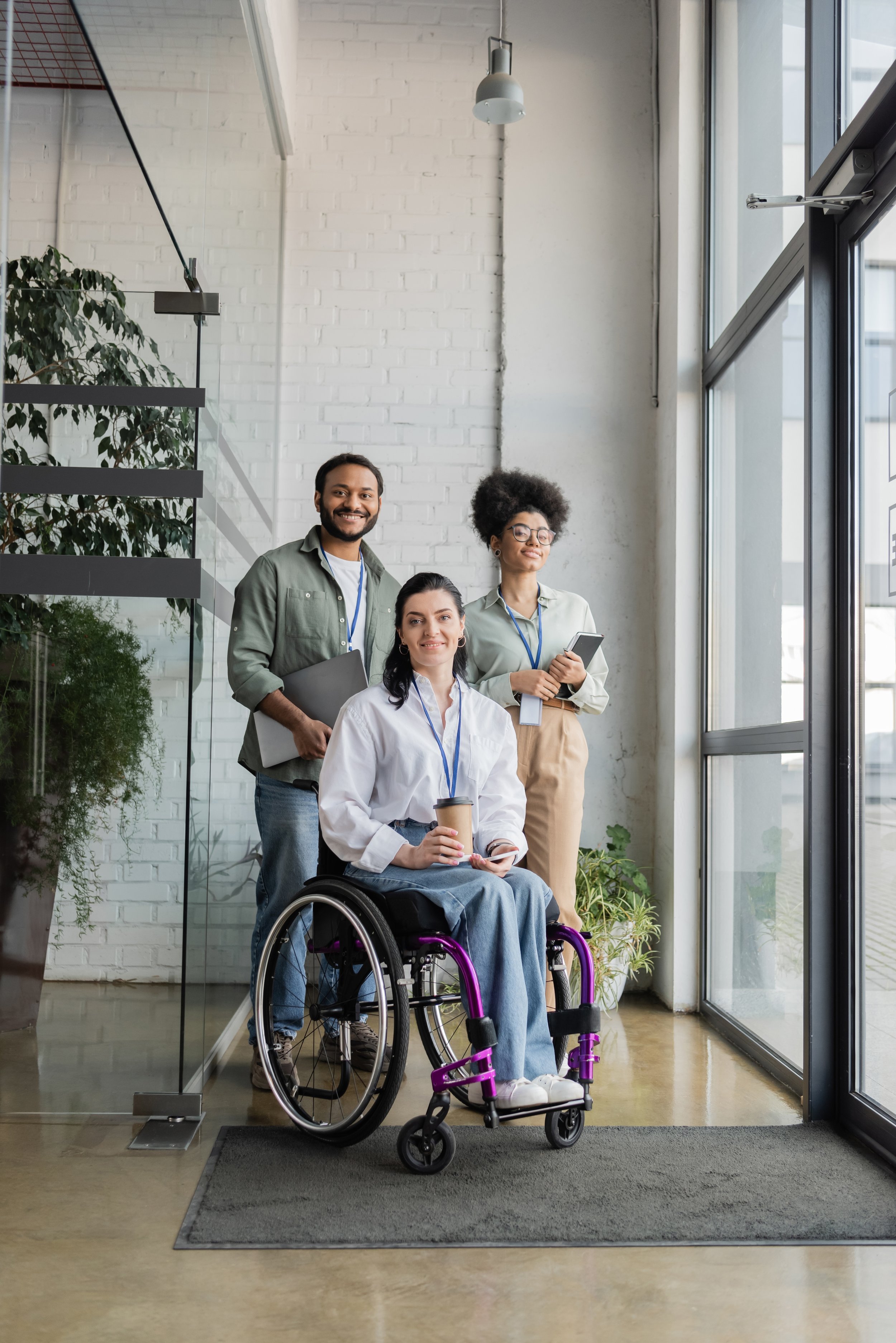 3 professionals - 2 standing behind one woman in a wheelchair