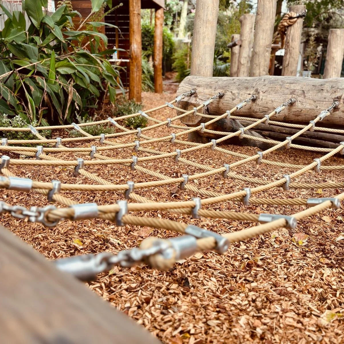 Although height is important for children to explore, climbing and clambering elements needn't be high to be meaningful. 

Here a cargo net is slung between two logs within a larger climbing zone. To traverse the full length of the space, children ne