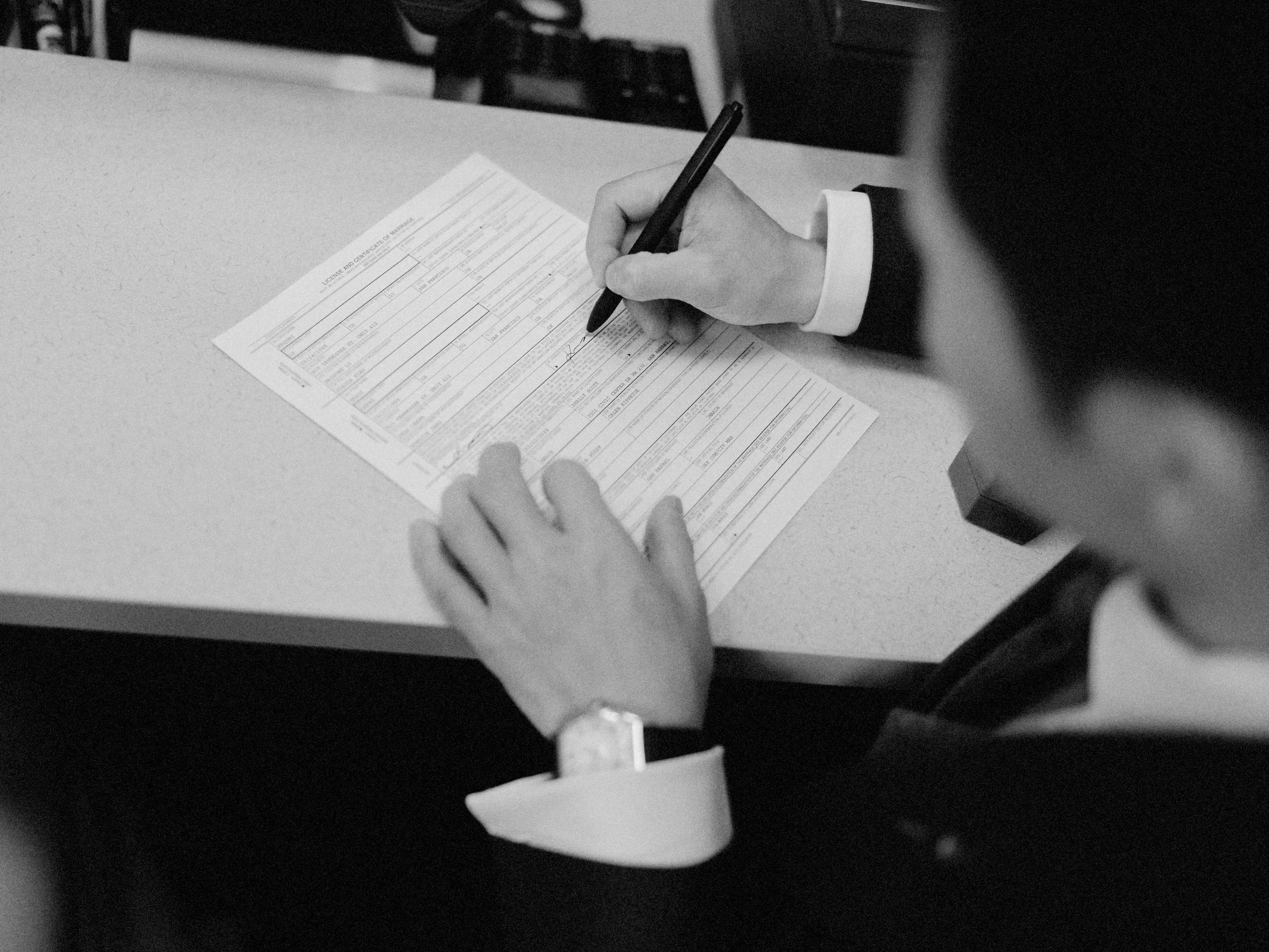 Man signing marriage license, photographed by san francisco courthouse wedding photographer​