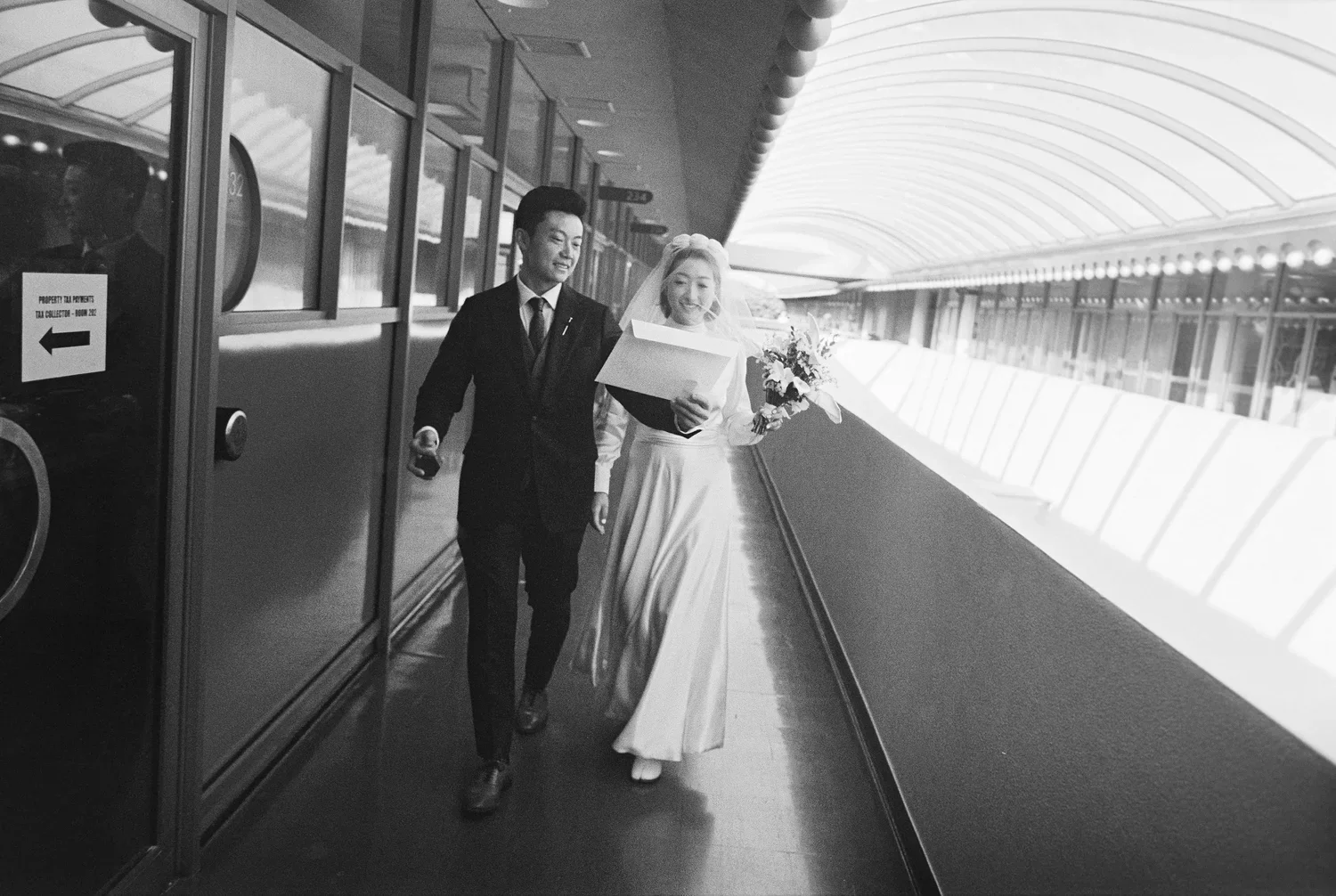 Couple walking down hallway with marriage license, taken by san francisco city hall elopement photographer​