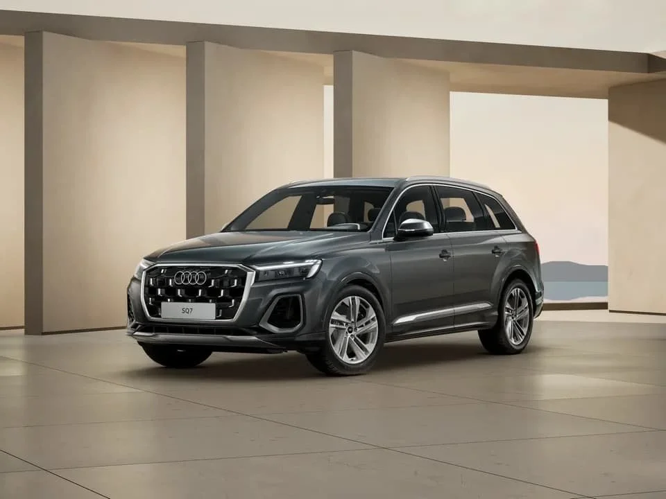Ein schwarzer Audi Q7 SUV steht in einem modernen, minimalistischen Raum mit neutralen Farben und großen Fenstern.