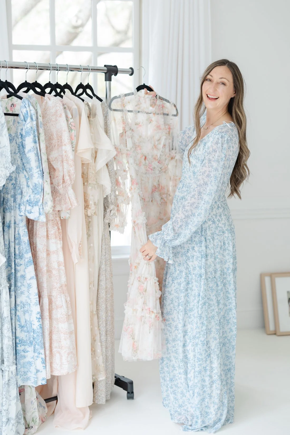 Behind-the-scenes look at outfit planning for family portraits, featuring soft, floral dresses in a studio wardrobe.