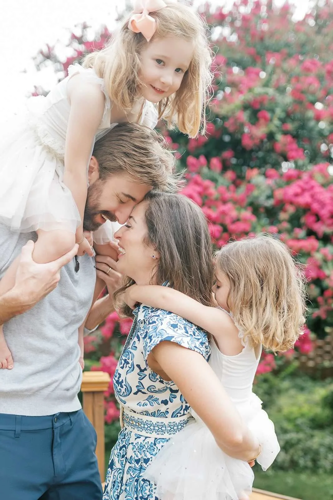 Mom and Dad touching foreheads while holding their daughters - Raleigh Newborn Photographer