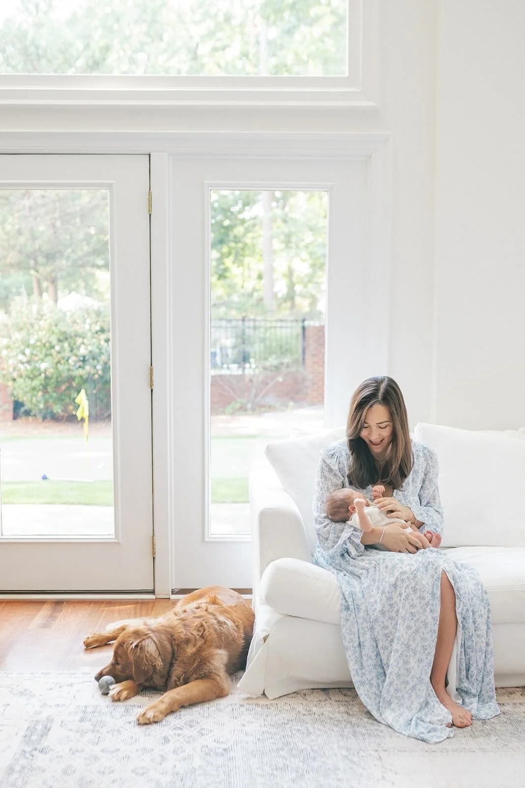 Mother holding baby boy in natural light with a sweet dog by her side - Raleigh Newborn Photographer