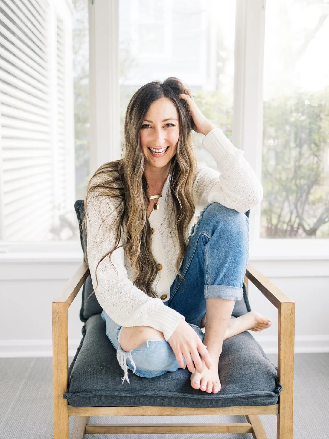 Lifestyle branding image of female photographer sitting in natural window light, sharing personality to show how to get photography clients authentically