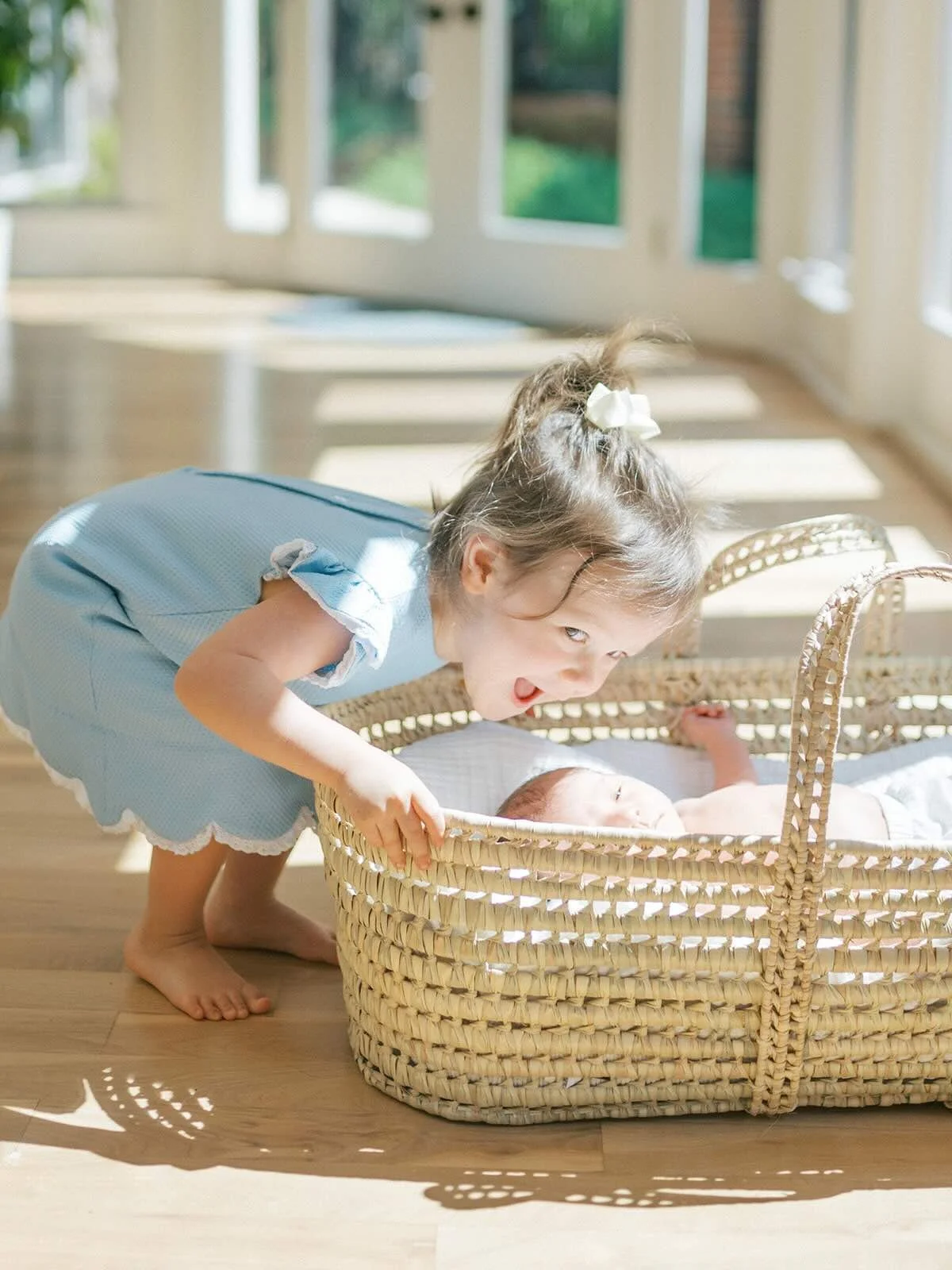 Big sister smiling at baby brother in the bassinet - Raleigh Newborn Photographer