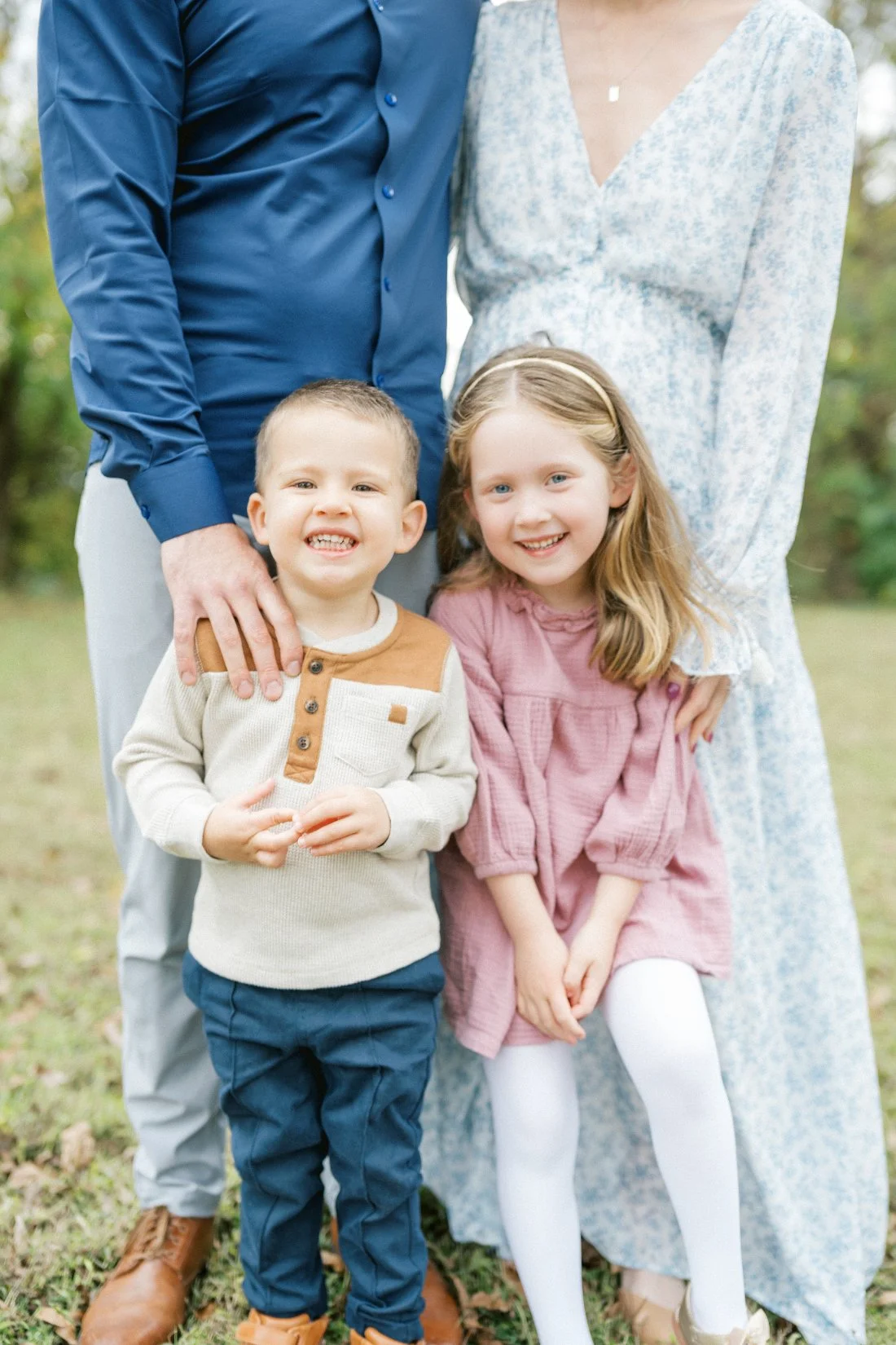 two young siblings smiling with their parents during an outdoor Raleigh family session.