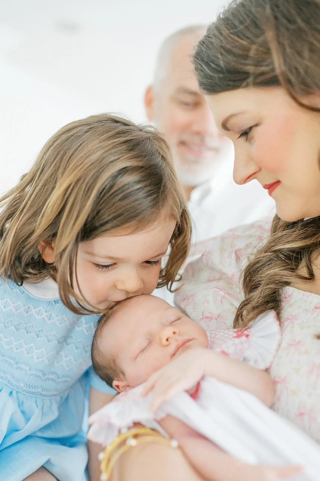 Big sister giving baby in mothers arms a kiss - Raleigh Newborn Photographer