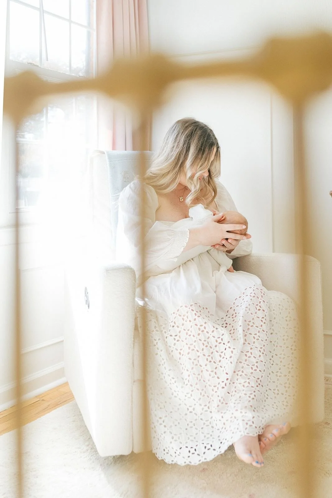A photo through the crib of mother nursing baby - Raleigh Newborn Photographer