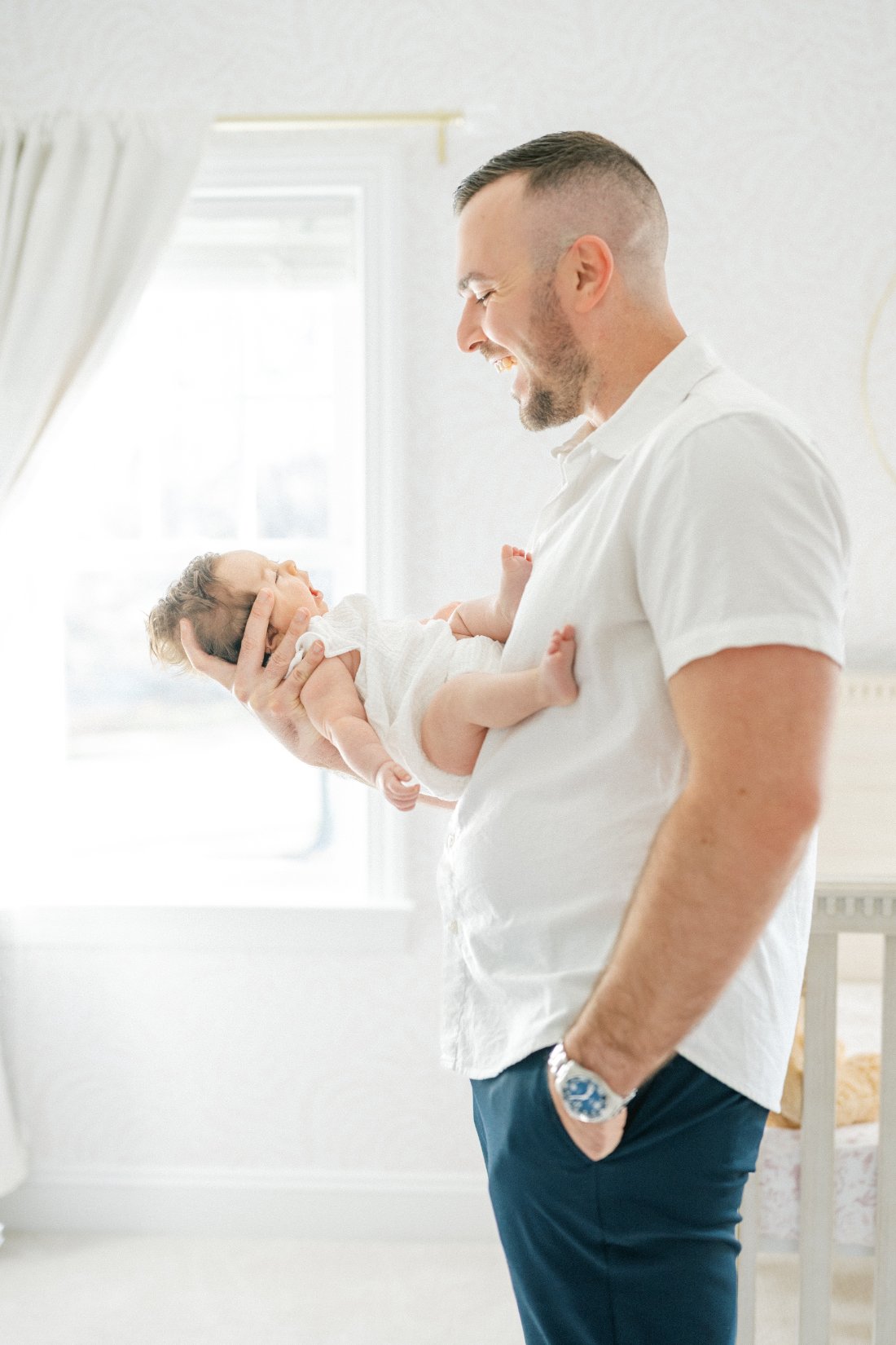 Father smiling at his newborn baby during an in-home session, showing how photography business ideas can center on meaningful client connections.