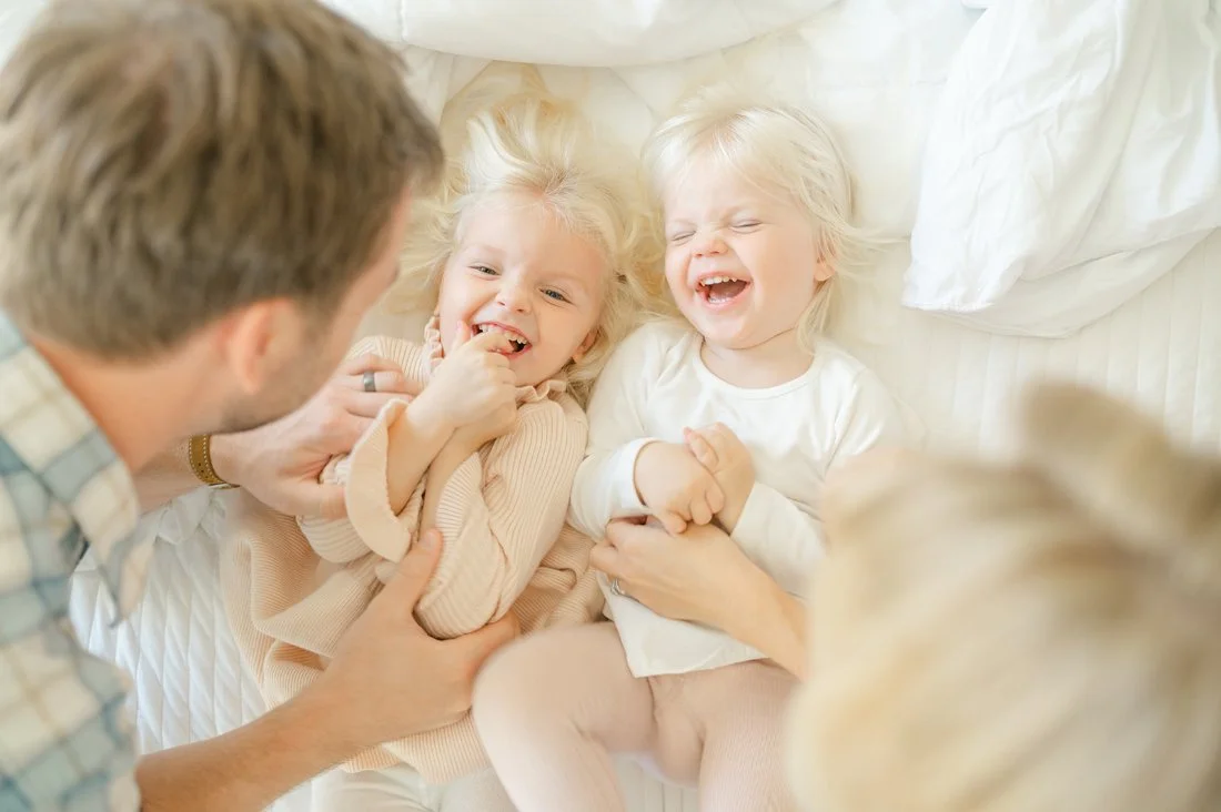 Family laughing together during an in-home lifestyle session while learning how to start a photography business that focuses on genuine connection.
