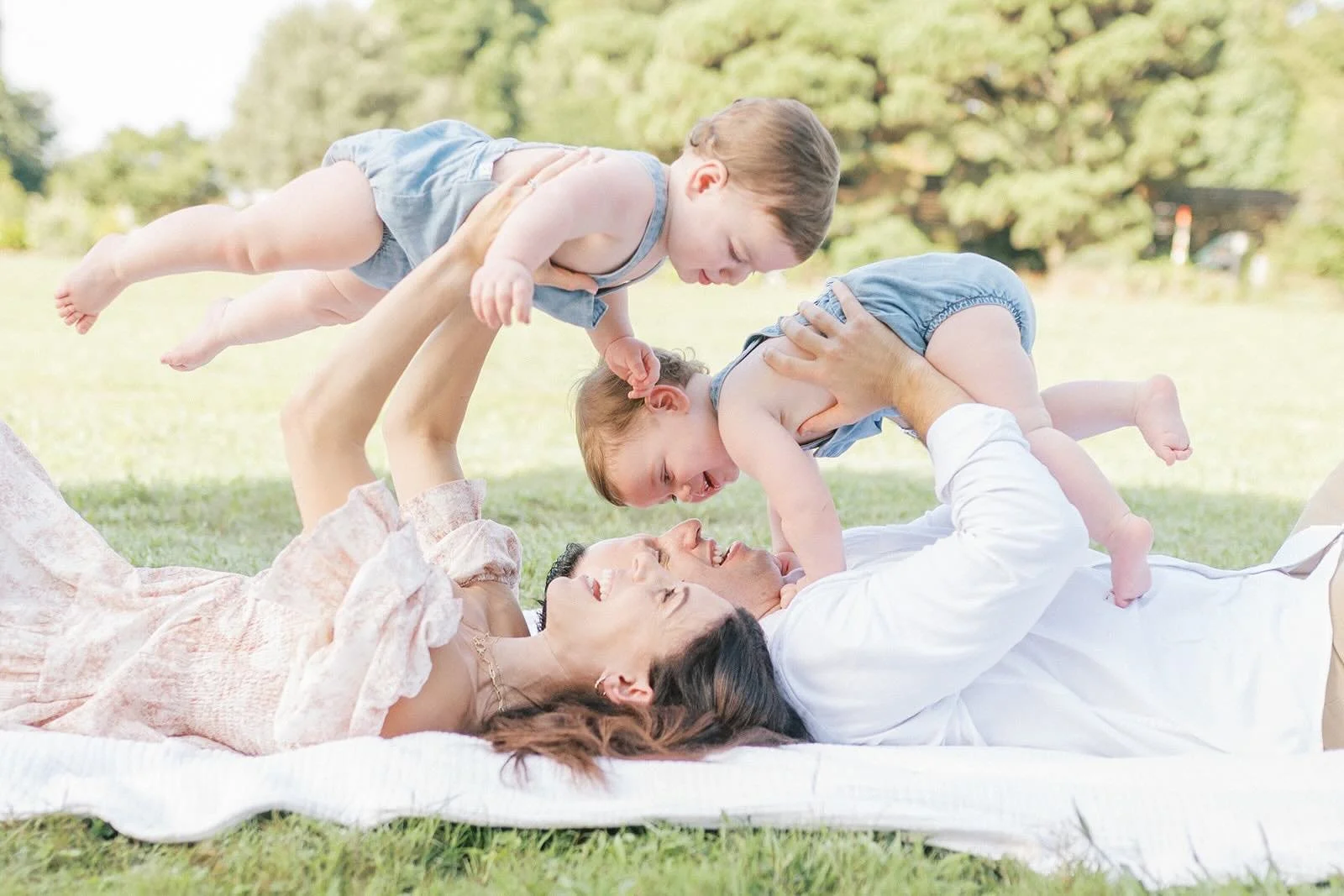 Mom and Dad lifting sons in the air while laying on a blanket - Raleigh Newborn Photographer