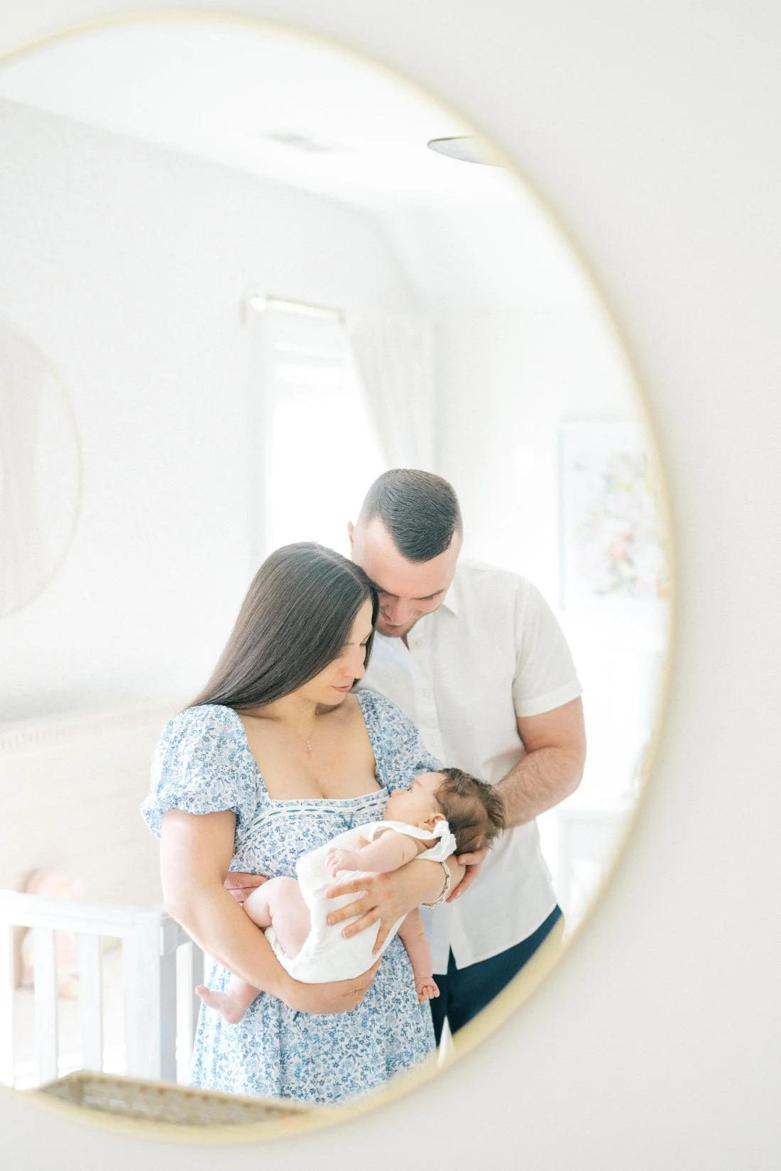 Parents holding their newborn together during a bright, intimate in-home newborn photography session.