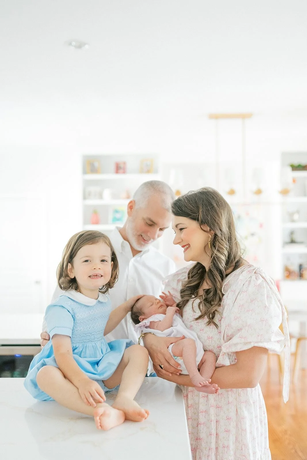 New family of four looking at each other lovingly in the kitchen - Raleigh Newborn Photographer