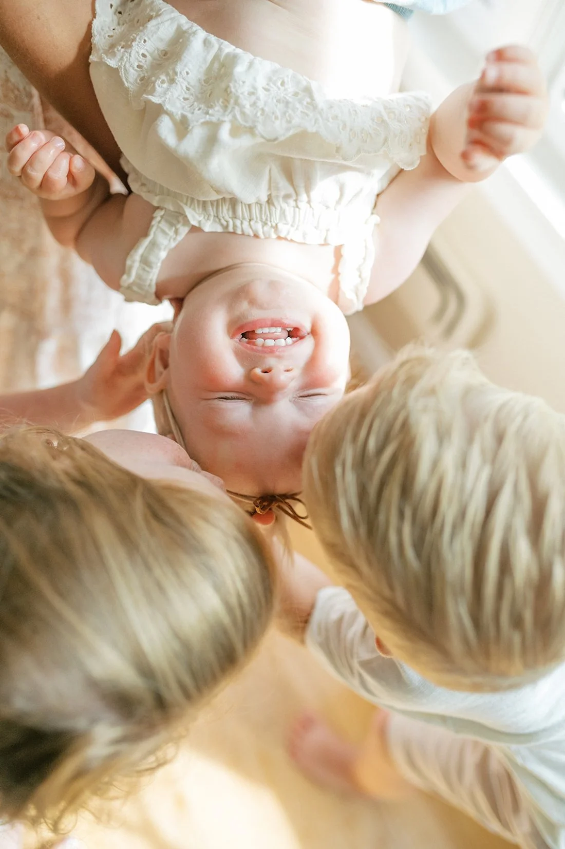Joyful baby laughing during an in-home family photography session, reminding photographers learning how to start a photography business to embrace real moments.
