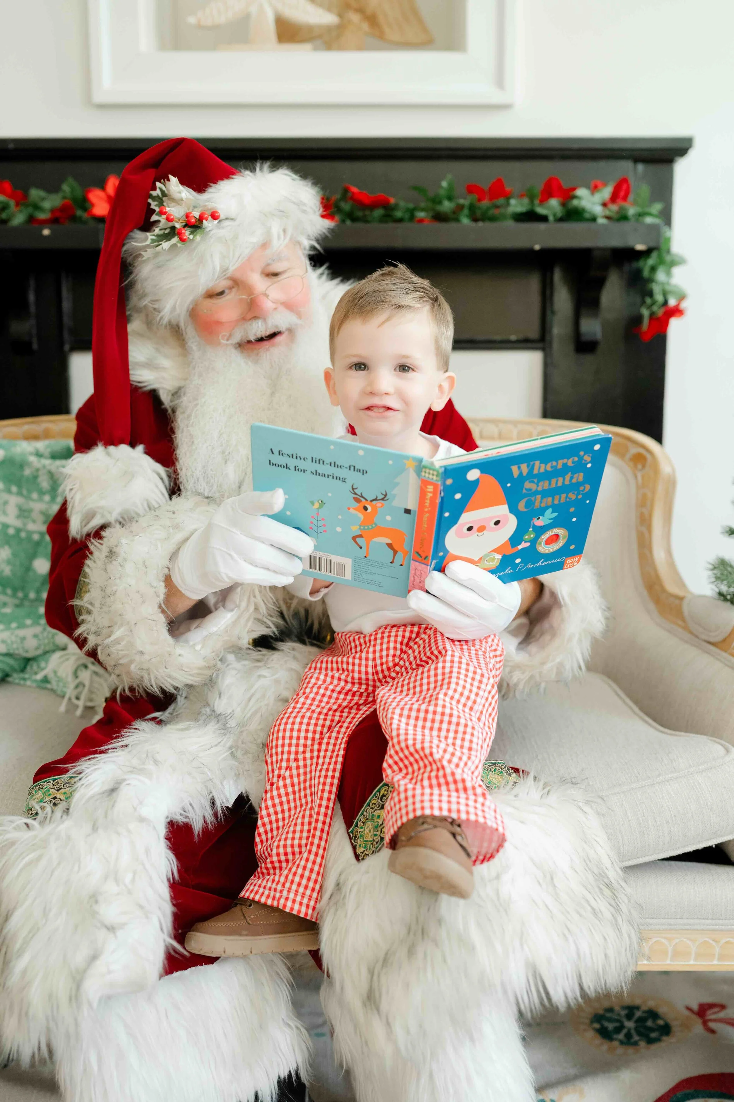Boy sitting on Santa's lap reading a book during their family Christmas Activity in Raleigh by Kelly Bullock Photography.