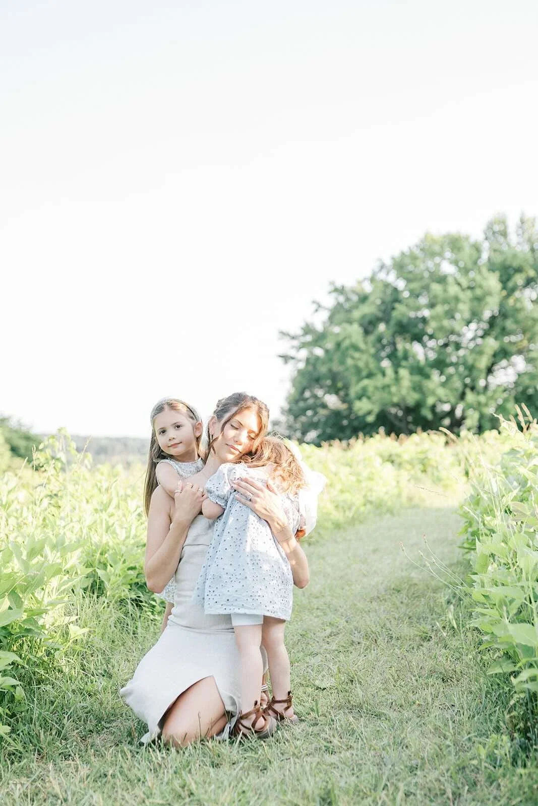 Mom getting hugs from her daughters in the outdoor light- Raleigh Newborn Photographer