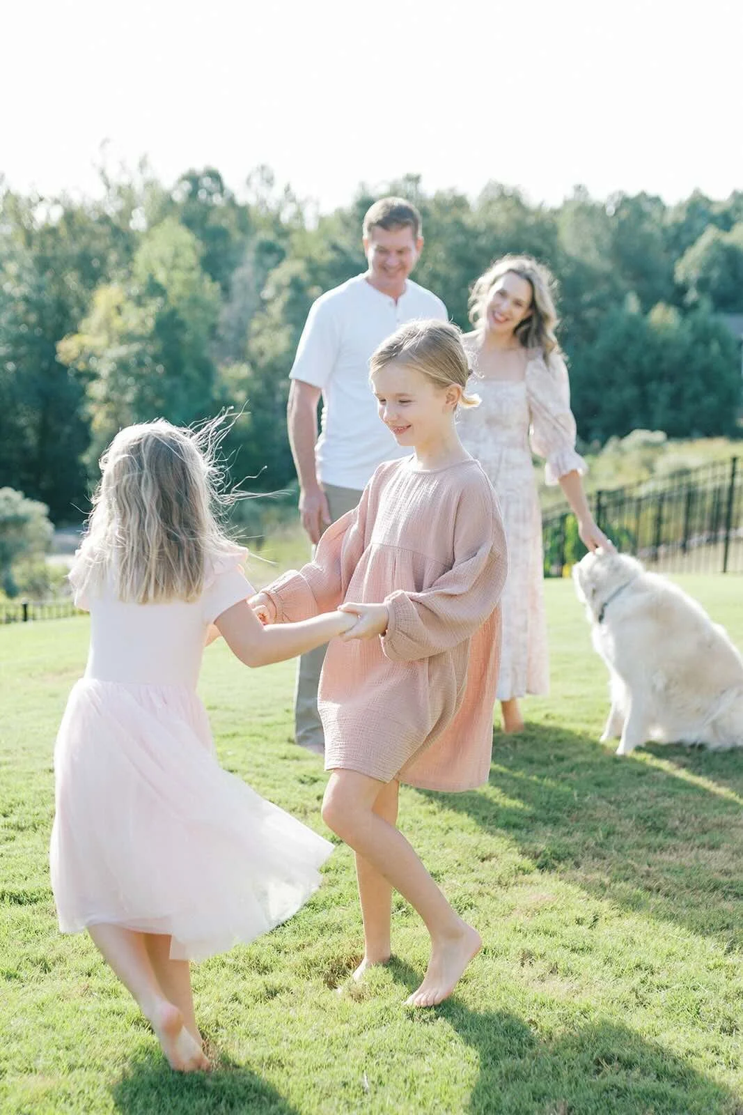 Mom and dad watching daughters twirl in the yard - Raleigh Newborn Photographer