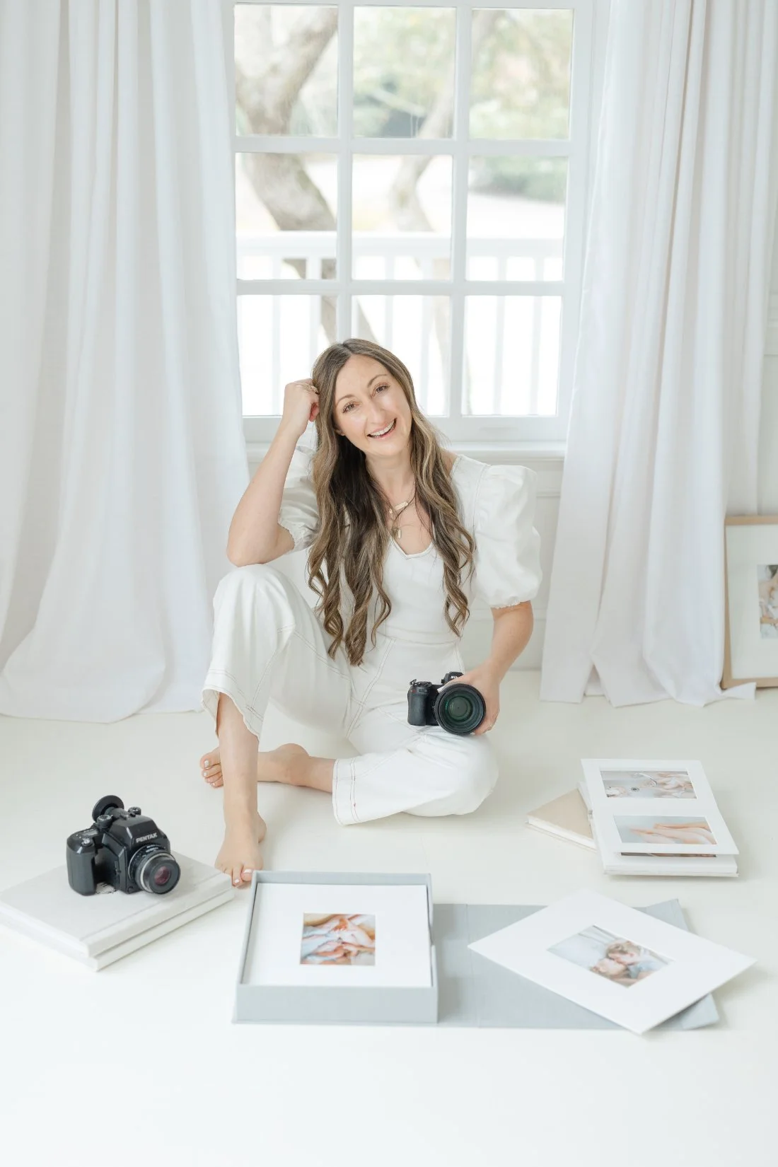 Kelly Bullock with camera and heirloom albums in her studio, sharing photography business mentoring for photographers.