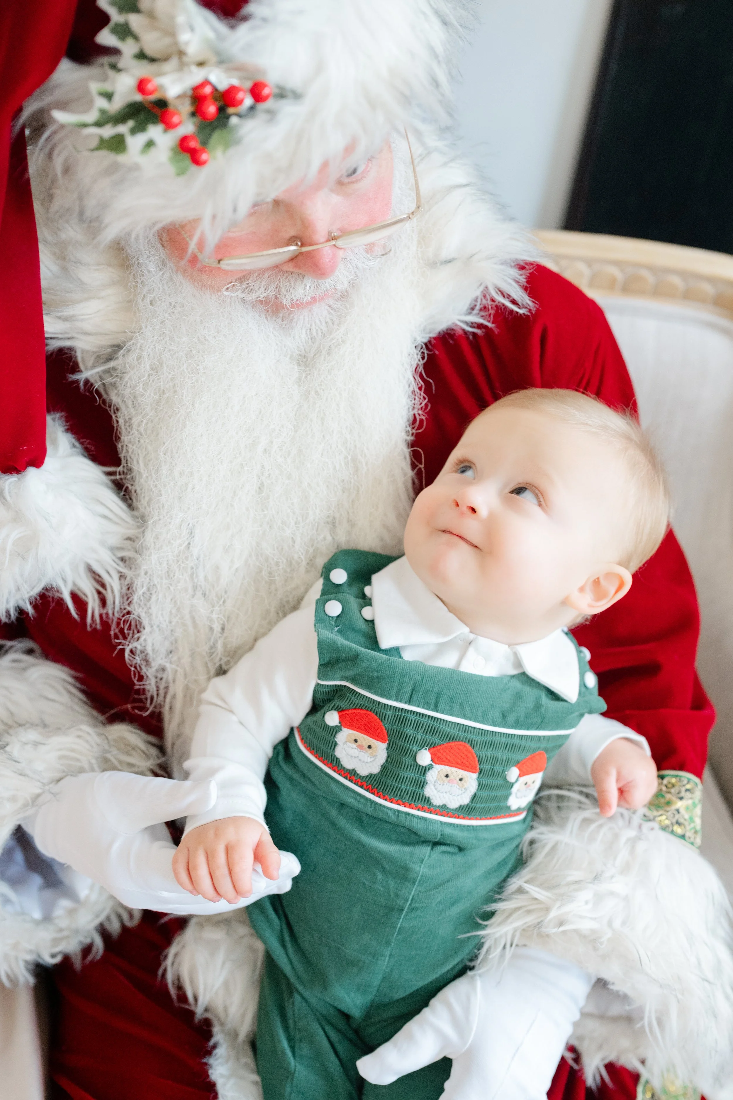 Little boy sitting in Santa's arms, looking up at him, and wondering when she will stop believing in Santa by Kelly Bullock Photography.