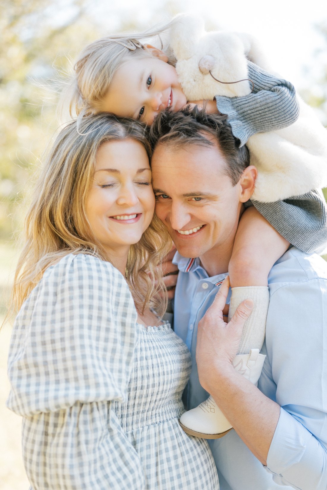 Joyful family cuddling outdoors, showing a connected and playful photography style focused on real interaction.