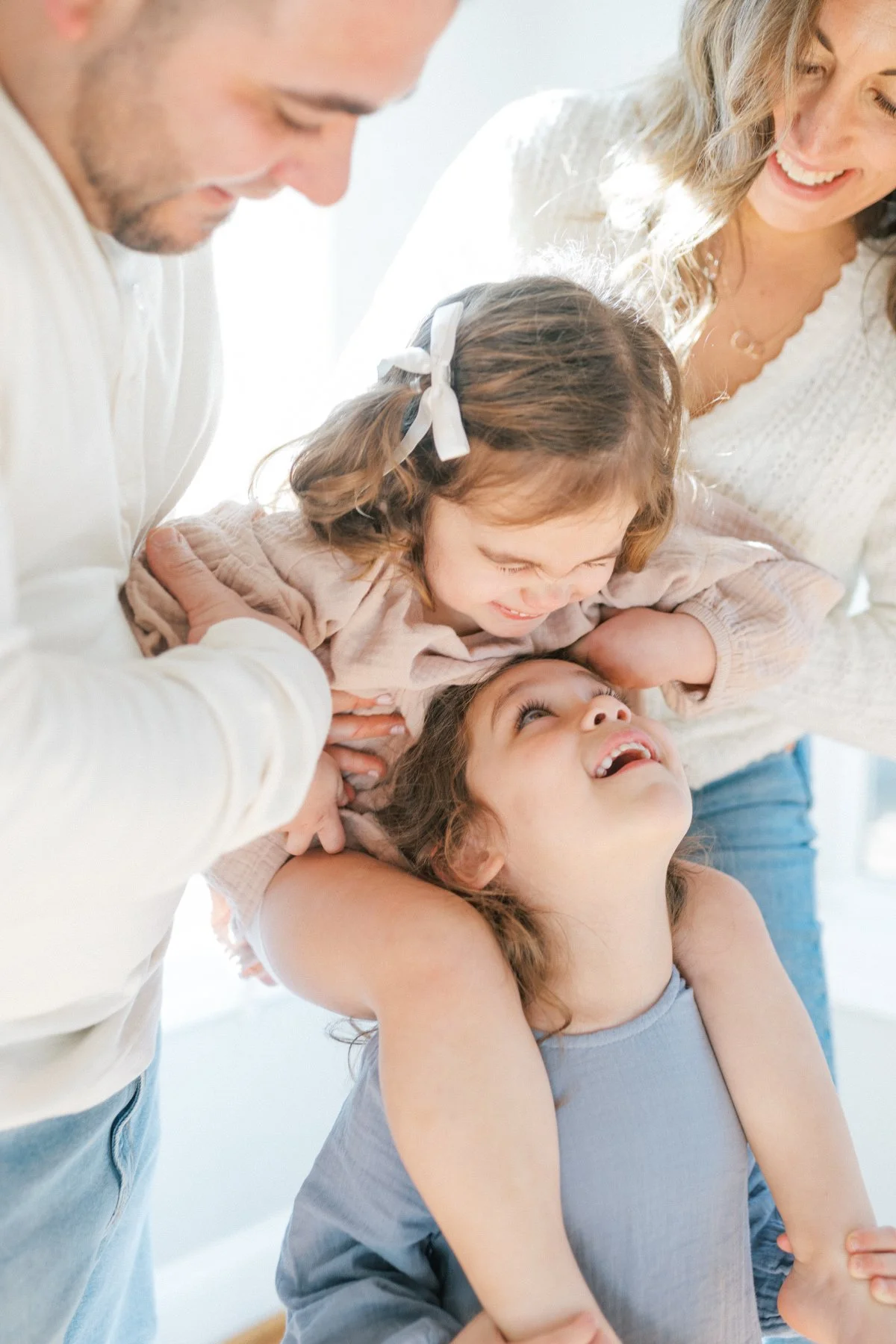A family sharing a playful moment with their children laughing and leaning into each other, beautifully showing how investing in memories preserves real connection.